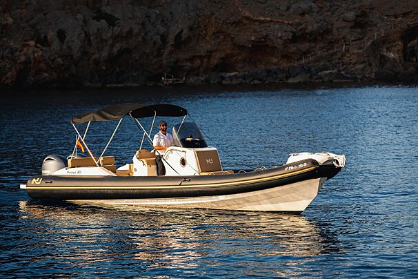 A man steers a black and white RIB