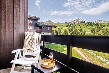 A balcony with a chair and a bottle of beer