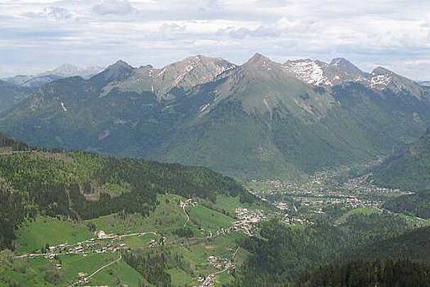 An aerial view of a valley surrounded by mountains and trees