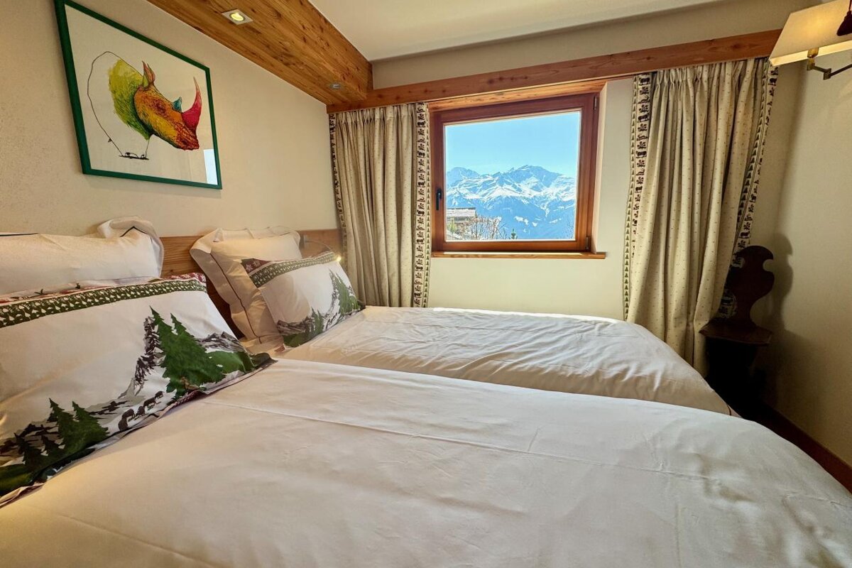 A bedroom with two beds and a window with mountains in the background
