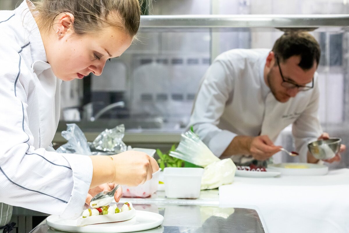 A man and a woman are preparing food in a kitchen