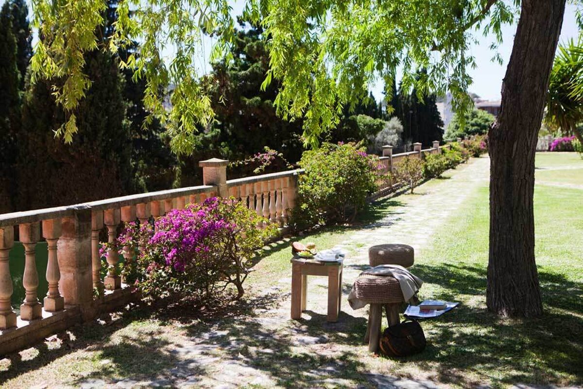 A wooden stool sits under a tree in a park