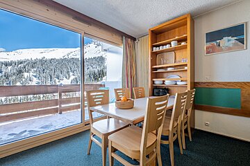 A dining room with a table and chairs and a picture on the wall