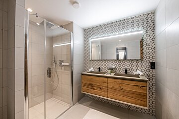 A bathroom with two sinks and a walk in shower