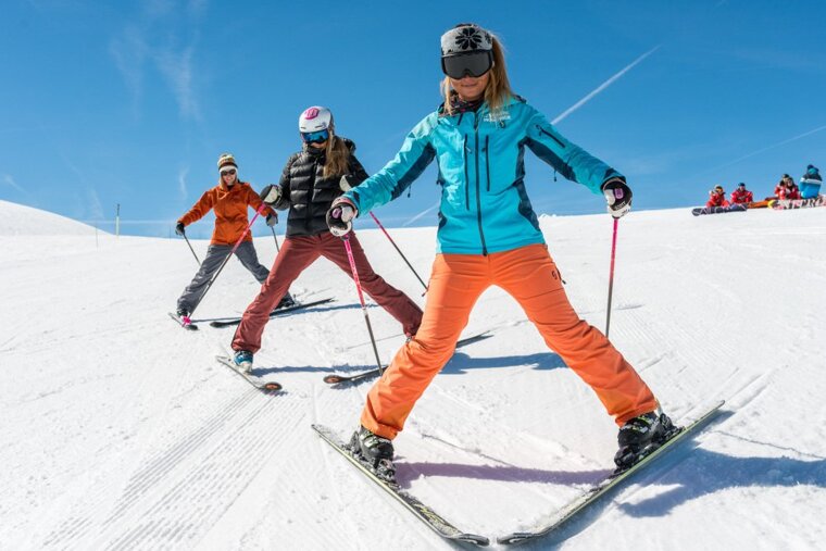 three people snow ploughing on skis