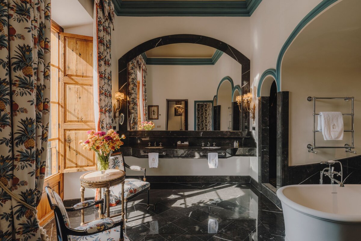 A bathroom with two sinks and a bathtub and a vase of flowers