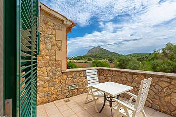 A balcony with a table and chairs with a mountain in the background