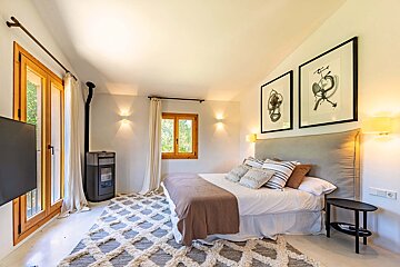A bedroom with a large bed and two paintings on the wall