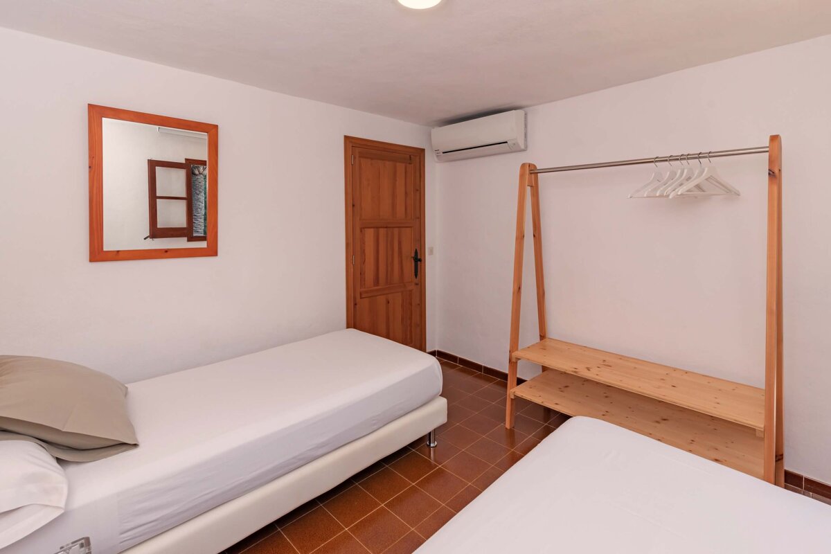 A bedroom with two beds and a clothes rack