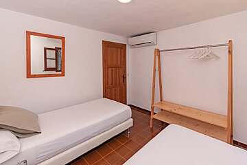 A bedroom with two beds and a clothes rack