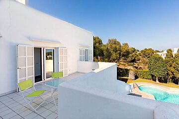 A balcony with a table and chairs overlooking a swimming pool