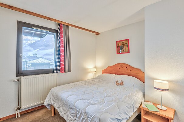 A bedroom with a bed a lamp and a window