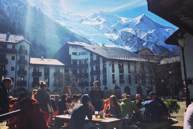 A group of people sitting at a picnic table in front of a chalet bar