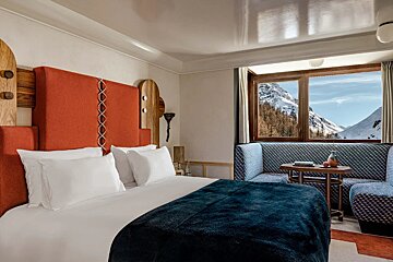 A hotel room with a bed and a window with mountains in the background