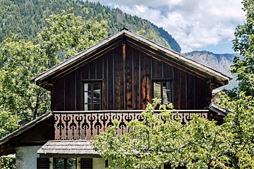 A wooden house with a balcony and mountains in the background