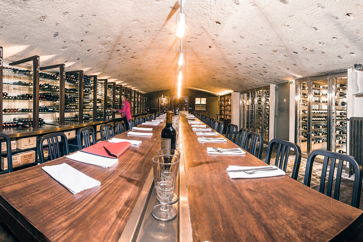 A long wooden table with a bottle of wine on it