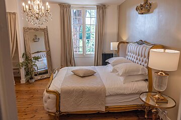 A bedroom with a bed a mirror and a chandelier