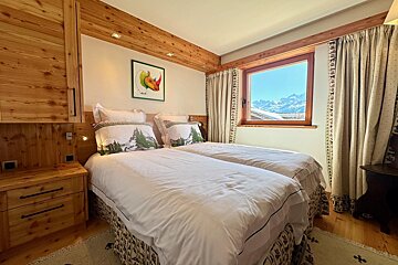 A bedroom with two beds and a window with mountains in the background