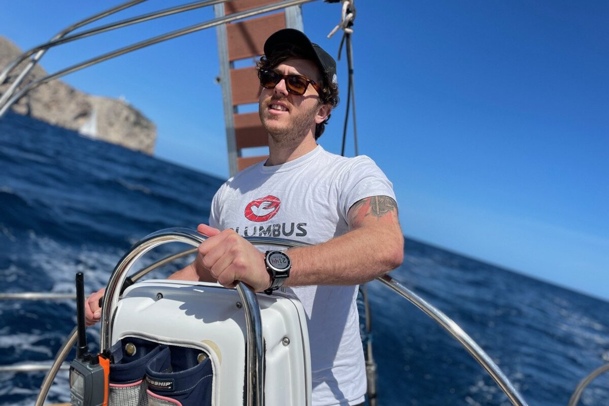 A man on a boat wearing a shirt that says columbus