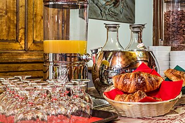A basket of croissants sits next to a bottle of orange juice