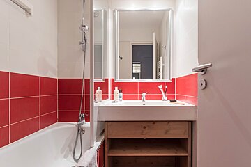 A bathroom with red tiles and a white sink