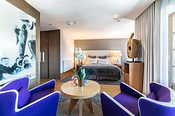 A hotel room with purple chairs and a table