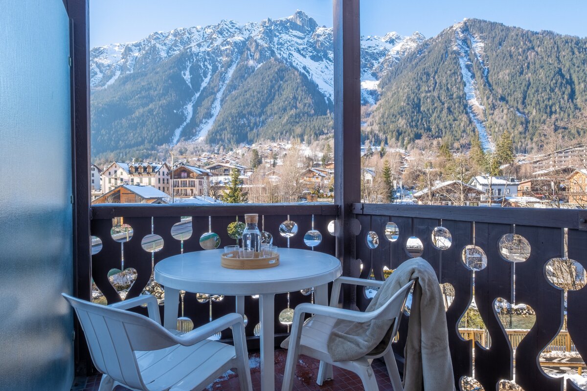 A table and chairs on a balcony with mountains in the background