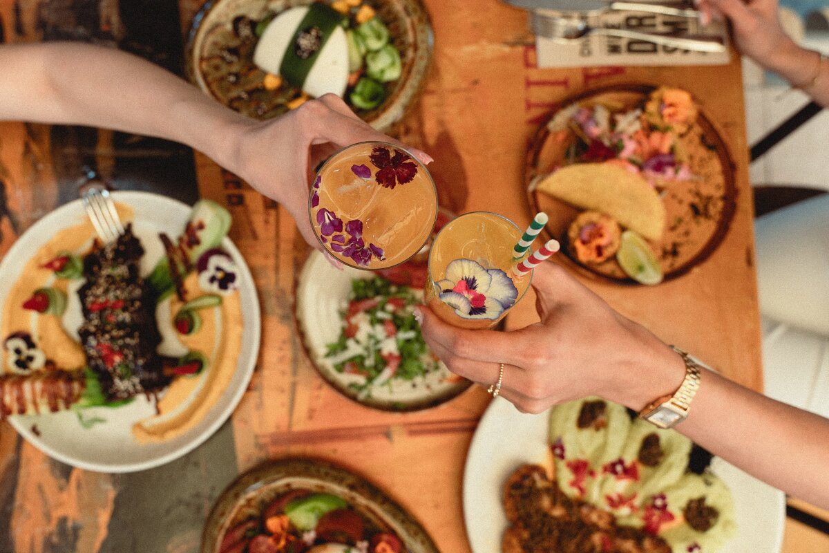 A group of people toasting with drinks and plates of food