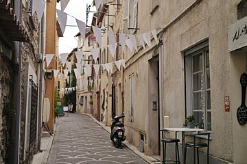 a narrow street in antiebs with a few shops and some bunting
