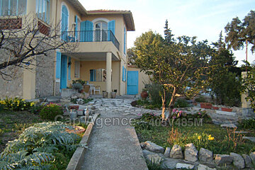 A large yellow house with blue shutters is for sale by car agence