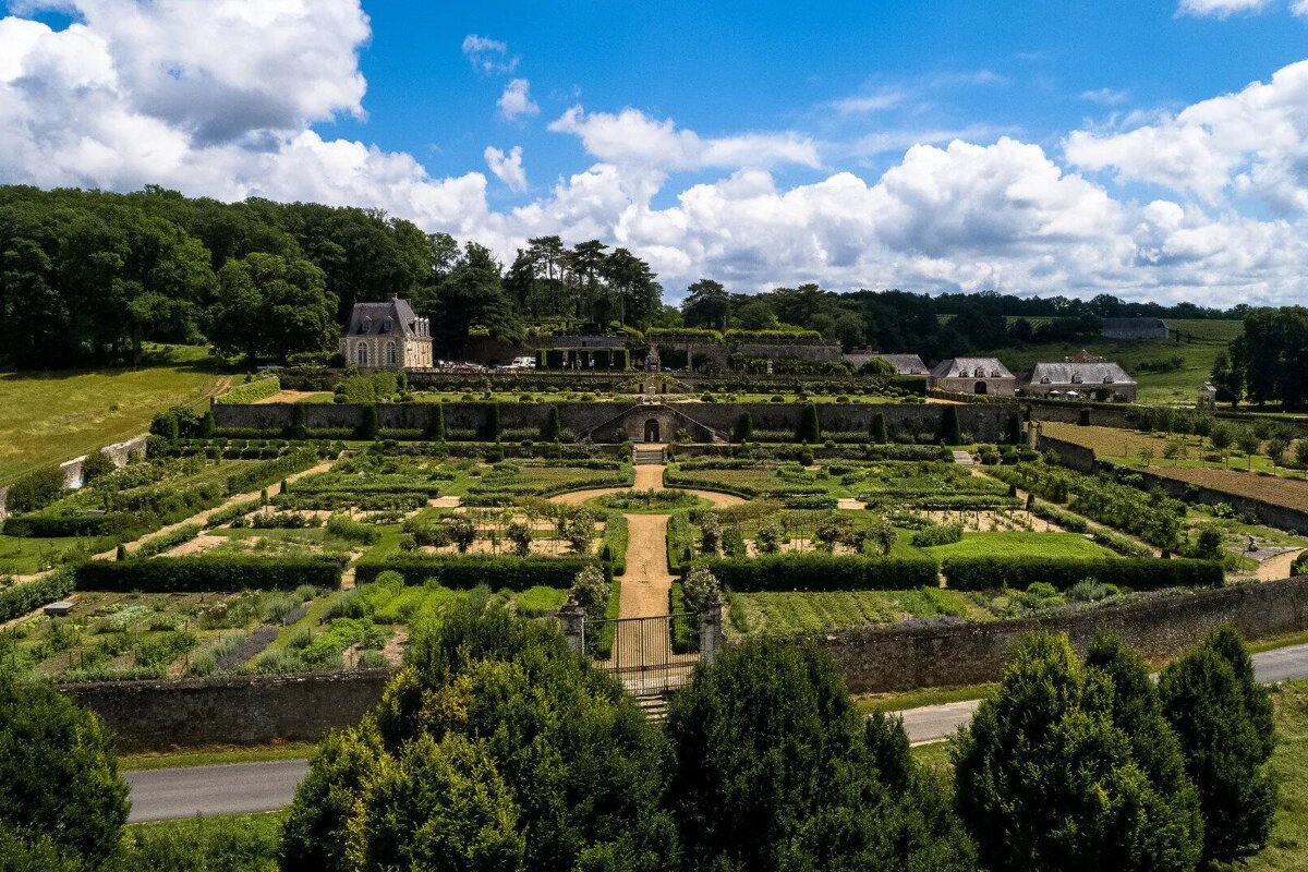 An aerial view of a large garden with a castle in the background