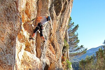 a picture of a person climbing on a sunny rock face