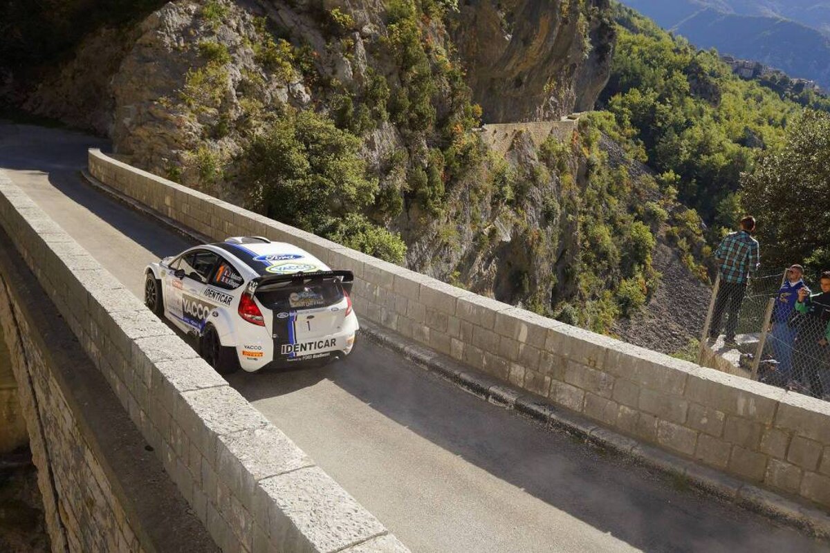 a rally car driving over a narrow bridge in antibes