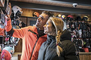 A man and a woman are looking at helmets in a store