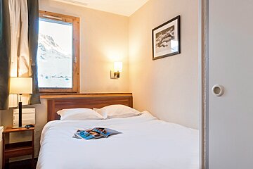 A small bedroom with a bed and a picture on the wall