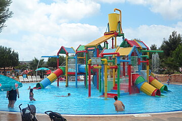 People playing in a pool with an umbrella that says kolise