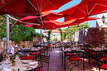 Tables and chairs under red umbrellas in a restaurant