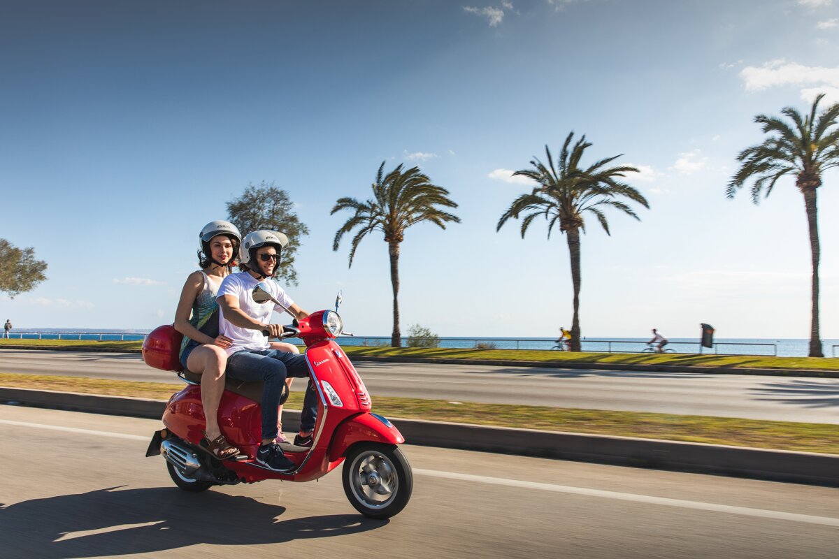 A man and a woman are riding a red scooter
