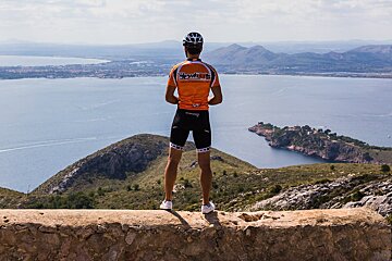 A man wearing an orange shirt that says ' schwalbe ' on it