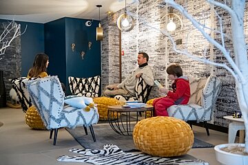 A boy sits in a chair reading a book in a living room