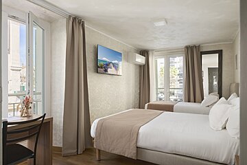 A hotel room with two beds and a television on the wall