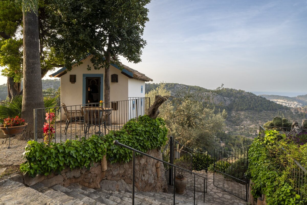 A small white house with a blue trim sits on top of a hill