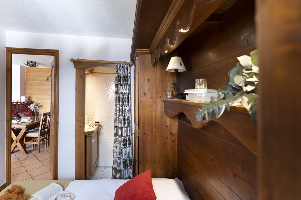A bedroom with a wooden wall and a bed with a red pillow