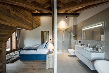 A bedroom with a blue bed next to a bathroom