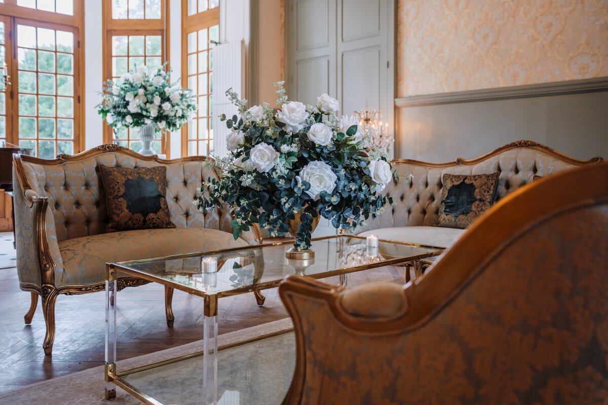 A vase of flowers sits on a glass table in a living room