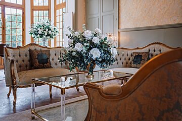 A vase of flowers sits on a glass table in a living room