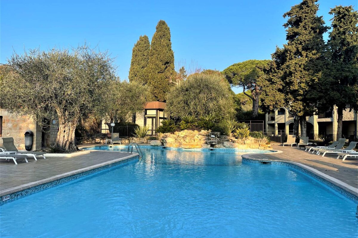 A large swimming pool surrounded by chairs and trees