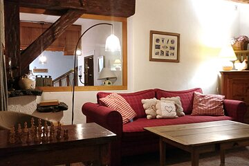 A living room with a red couch and a chess board