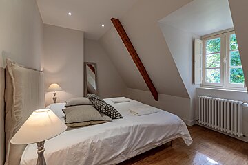 A bedroom with a bed a lamp and a window