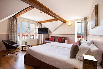 A hotel room with two beds a couch and a flat screen tv